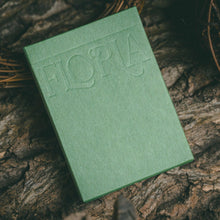 Load image into Gallery viewer, Green book with 'Floria' embossed on it, placed on a textured surface
